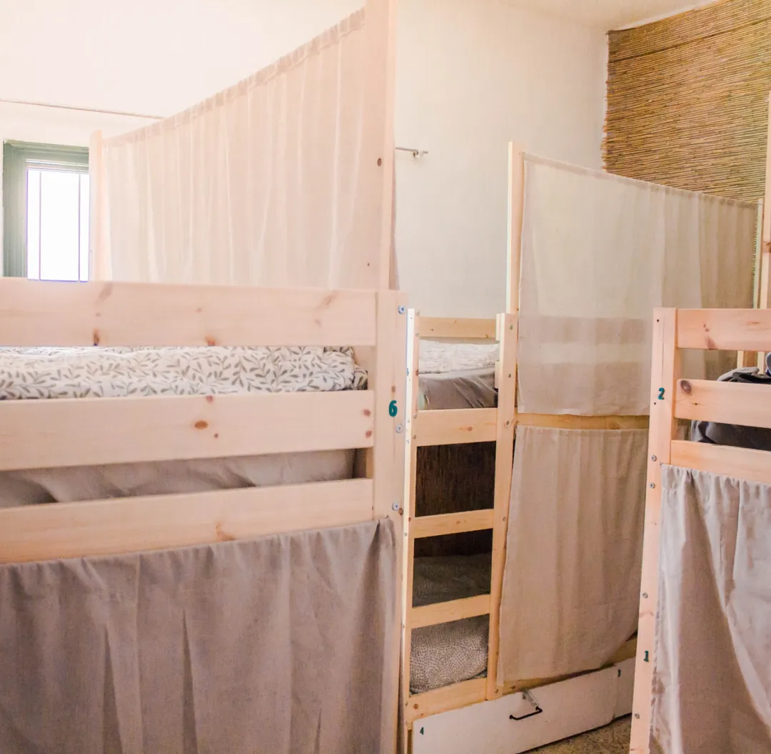 Habitación compartida del hostel Habitación compartida de Single Fin Surf Hostel con literas de madera y cortinas para dar privacidad