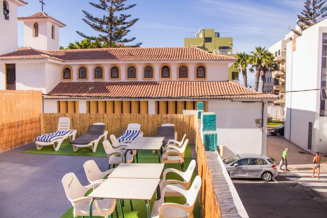 Terraza de Single Fin Surf Hostel Terraza soleada de Single Fin Surf Hostel con tumbonas, mesas y césped artificial